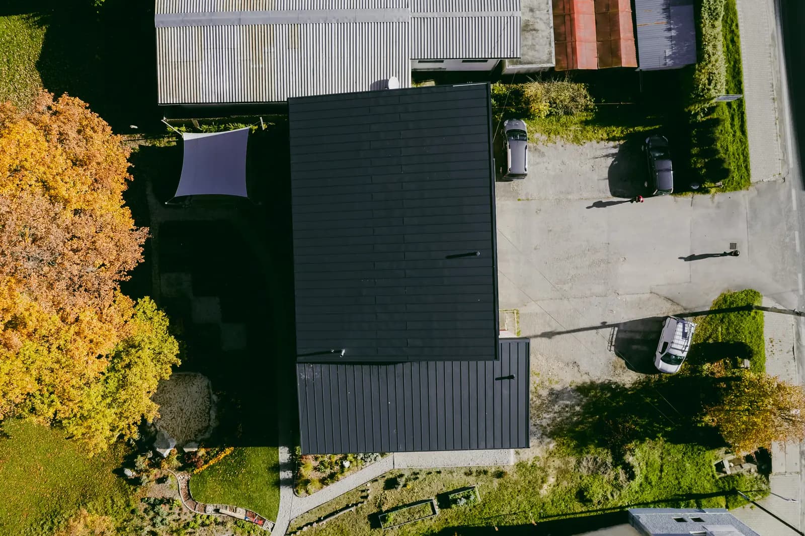 Strecha domu služieb z tmavosivého click panelu zhora z dronu, Nižná