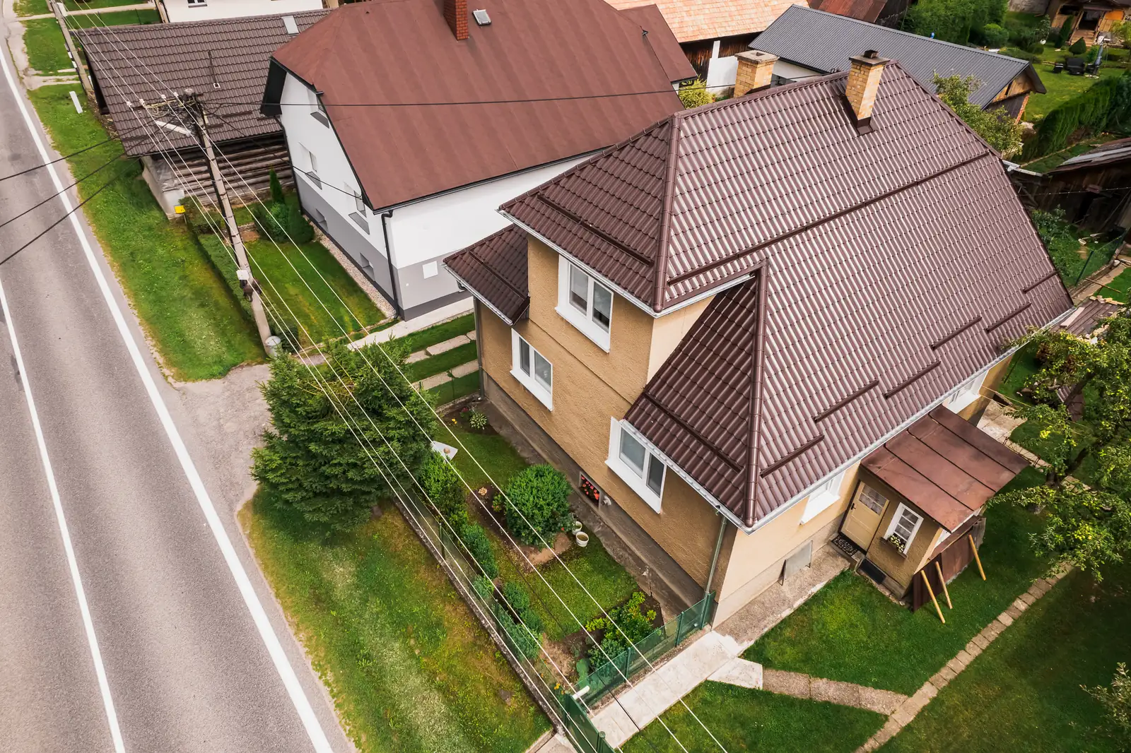 Valbová strecha z hnedého škridloplechu na rodinnom dome pri ceste v Krivej