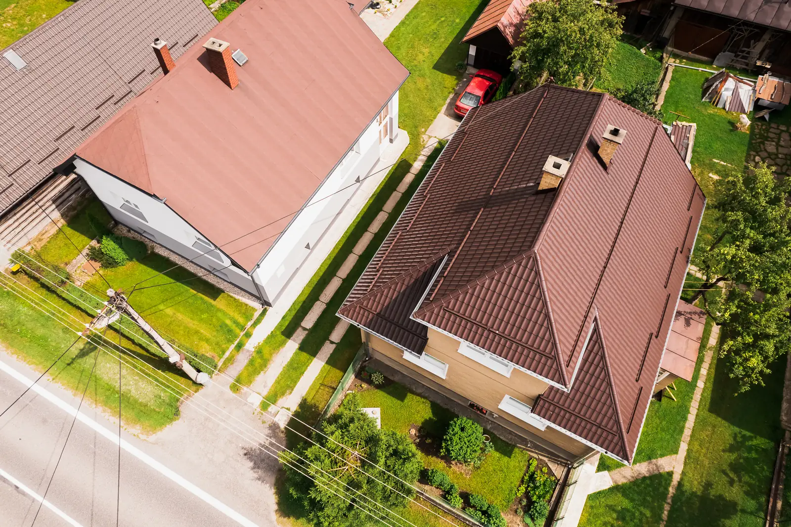 Strecha z hnedého škridloplechu s komínom zhora z dronu, rodinný dom v Krivej
